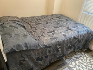 a bed with a gray comforter in a bedroom at Oshawa Duplex in Oshawa