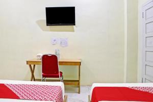 a room with a desk and a tv and a red chair at Hotel O Permata Inn in Banjarmasin +20 photos