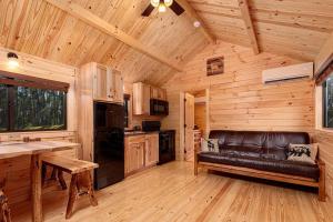 a kitchen with a leather couch in a wooden cabin at Cowan Creek Lodges in Centre