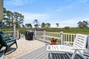 a deck with two white chairs and a fence at Kitty's Bayside Bungalow in Black Point Landing