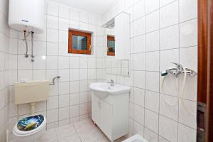e bagno piastrellato bianco con servizi igienici e doccia. di Apartments with a parking space Stupin Celine, Rogoznica - 23812 a Rogoznica (Rogosnizza) Altre 20 foto