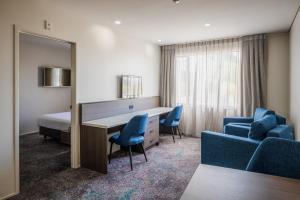 a hotel room with a bed and a desk and chairs at Heartland Hotel Auckland Airport in Auckland