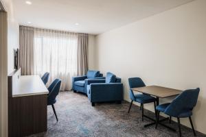 a waiting room with blue chairs and a table at Heartland Hotel Auckland Airport in Auckland