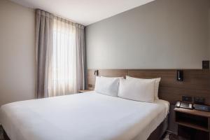 a bedroom with a large white bed and a window at Heartland Hotel Auckland Airport in Auckland