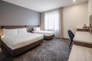 a hotel room with two beds and a desk at Heartland Hotel Auckland Airport in Auckland
