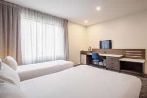a hotel room with two beds and a desk at Heartland Hotel Auckland Airport in Auckland