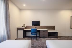 a room with a desk with a computer and a blue chair at Heartland Hotel Auckland Airport in Auckland
