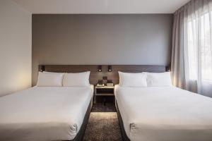 a hotel room with two beds and a window at Heartland Hotel Auckland Airport in Auckland