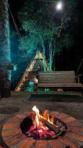 a fire pit in front of a park bench at night at Chalés Recanto do Vale - TUCANO in Bom Jardim da Serra