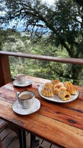 a wooden table with two plates of pastries and cups of coffee at Chalés Recanto do Vale - TUCANO in Bom Jardim da Serra +45 photos