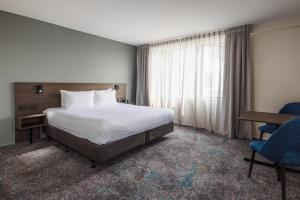 a hotel room with a bed and a desk and a window at Heartland Hotel Auckland Airport in Auckland