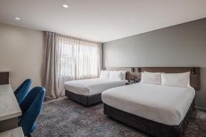 a hotel room with two beds and a window at Heartland Hotel Auckland Airport in Auckland