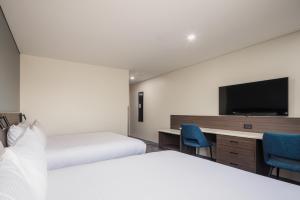 a hotel room with two beds and a flat screen tv at Heartland Hotel Auckland Airport in Auckland