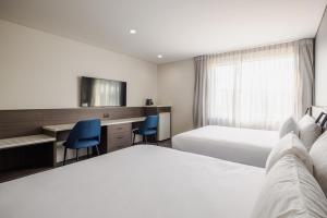a hotel room with two beds and a desk at Heartland Hotel Auckland Airport in Auckland