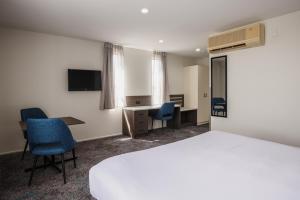 a hotel room with a bed and a desk and chairs at Heartland Hotel Auckland Airport in Auckland