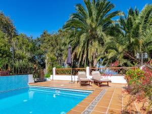 a pool with two chairs and a umbrella and palm trees at Charming Retreat in Fontanales with Pool in Moya