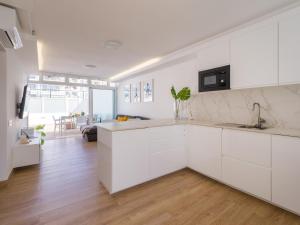 Una cocina con gabinetes blancos y una sala de estar. en Bungalow in Maspalomas near Golf & Beach, en San Bartolomé
