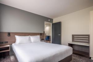 a bedroom with a large white bed and a desk at Heartland Hotel Auckland Airport in Auckland
