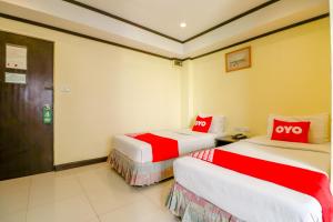 due letti in una stanza con rosso e bianco di Hotel Win Long a Bangkok