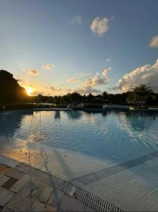 une grande piscine avec vue sur le coucher du soleil en arrière-plan dans l'établissement The Experience Iloa Residenci, à Barra de São Miguel