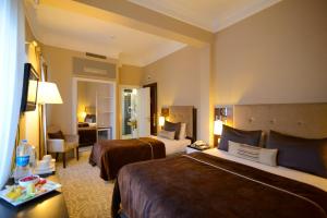 伊斯坦布尔City Center Hotel Taksim İstanbul的一间有两张床和一间客厅的酒店房间