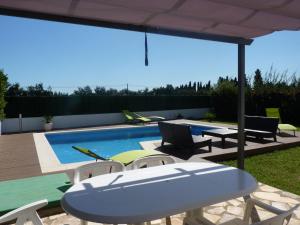 un patio con mesa y sillas y una piscina en Belvilla by OYO Bon Relax II45 en Sant Pere Pescador