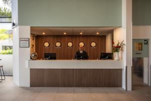 an office with clocks on the wall and a man sitting at a counter at Heartland Hotel Auckland Airport in Auckland +37 photos