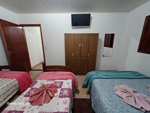 カンポス・ド・ジョルドンにあるApartamento Kit 01, em Campos do Jordãoのベッドが2つと壁にテレビがある部屋