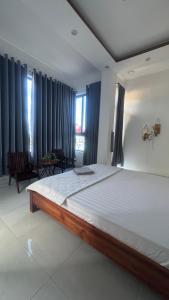 a bedroom with a large bed with blue curtains at SÓNG Coffee & Homestay in Quy Nhon +8 photos