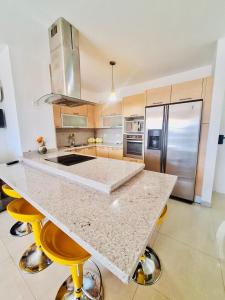eine Küche mit einer großen Insel mit gelben Barhockern in der Unterkunft Coral Plaza Lechería Vacaciones cerca de playa in El Morto de Barcelona
