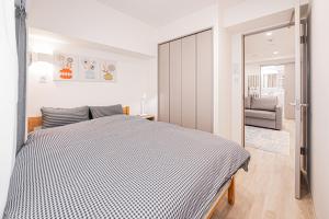 Un dormitorio con una cama con un edredón blanco y negro. en self-check in misimaya building, en Tokio