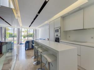 una cocina con armarios blancos y una barra larga con taburetes en Holiday Home in Spain near the Beach & Marina, en San Bartolomé