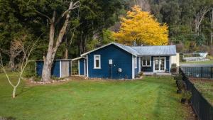 哈夫洛克Fantail Cottage Kaiuma Bay - Havelock Holiday Home的一座有树的院子中的蓝色房子