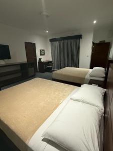 Una habitación de hotel con tres camas y un televisor. en Scala Inn, en Muelle