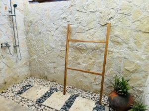 a shower with a ladder in a bathroom with rocks at Sumba Voyage Villa in Rua