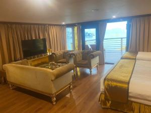une chambre d'hôtel avec un lit, un canapé et une télévision dans l'établissement Golden Cruise luxury, à Hạ Long
