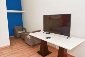 a living room with a tv on a white table at Hotel y Restaurante Santa Fe in La Libertad