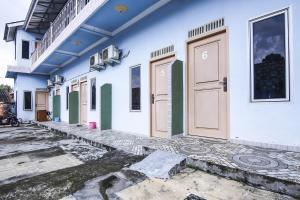 a blue and white building with doors on it at OYO Life 90433 Serasi Kost in Palembang