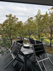 a table and chairs on a balcony with trees at Cockatoo Retreat in Belmont