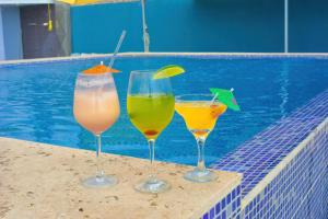 three drinks sitting on a ledge next to a swimming pool at Hotel y Restaurante Santa Fe in La Libertad