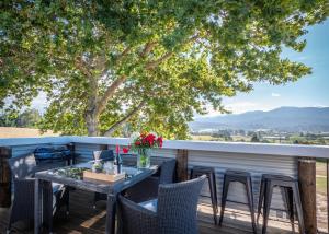 einen Tisch und Stühle auf einer Terrasse mit Aussicht in der Unterkunft Mariri Heights Sequoia Cottage in Lower Moutere