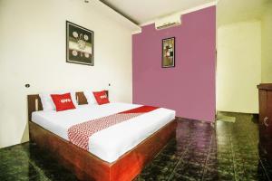 ein Schlafzimmer mit einem Bett mit roten und violetten Wänden in der Unterkunft Hotel O Nyi Rindang Near Puskesmas Jekan Raya in Palangkaraya + 19 Fotos