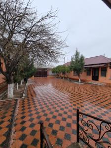 a brick courtyard with a checkered floor in front of a building at Ziyarat Guest House in Türkistan