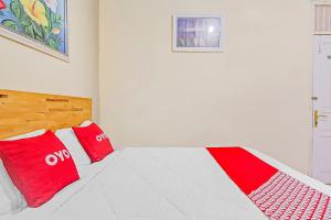 a white bedroom with red pillows on a bed at Hotel O New Bunga Sonsang Homestay Syariah in Padang