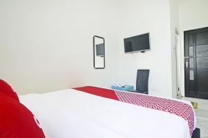 una camera da letto bianca con un letto e una TV di Hotel O Papi Inn Guesthouse a Palangkaraya