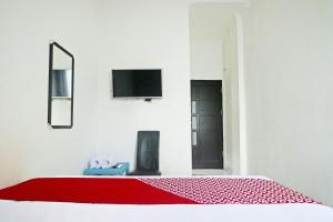 Camera bianca con letto e coperta rossa di Hotel O Papi Inn Guesthouse a Palangkaraya