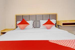 a bed with red and white pillows on it at Capital O 90635 Tango Juliet Residence in Jakarta