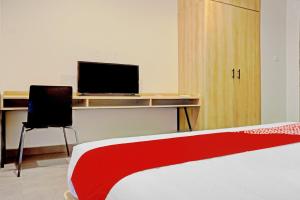 a bedroom with a bed and a desk with a television at Capital O 90635 Tango Juliet Residence in Jakarta +31 photos