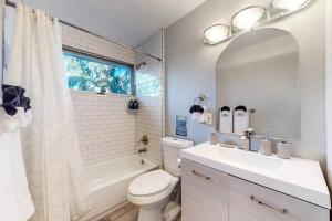 a white bathroom with a sink and a toilet and a tub at Sunny Family Home in Denver with huge yard and hot tub in Denver
