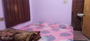a bedroom with a bed with a pink comforter at JMS Girls Hostel in Varanasi